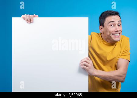Uomo eccitato che mostra banner in bianco in studio Foto Stock