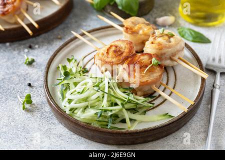 Dieta chetogenica. Disintossicazione e concetto sano. Involtini di pancetta avvolta pollo desiderio cetrioli e ravish microgreens. Foto Stock