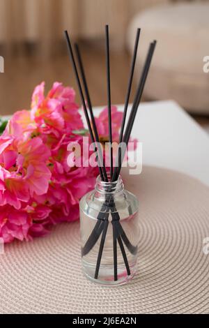 diffusore di canne aromatiche e bellissimi fiori sul tavolo bianco a casa Foto Stock