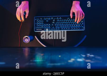 Le mani dei videogamer professionisti su tastiera e mouse per computer da gioco professionali in colore neon Foto Stock