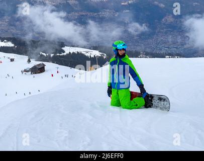 Ragazzo in casco, occhiali e ginocchiere snowboard sulla neve pendenza, vista  frontale Foto stock - Alamy