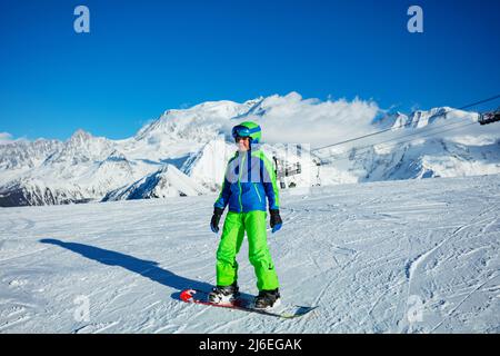 Ragazzo sullo snowboard in maschera e casco completo per snowboarder Foto Stock