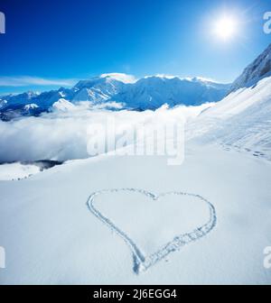 Forma del cuore innevata in montagna sulle cime alpine Foto Stock