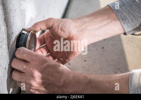 Lavoro caucasico Installazione di illuminazione da giardino con cortile a LED all'interno di elementi architettonici in calcestruzzo. Sistemi di illuminazione residenziale a 12 V. Foto Stock