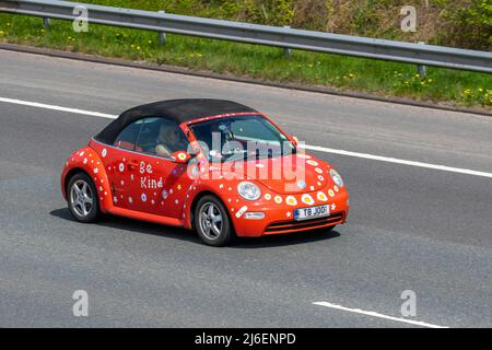 "BE Kind" 2004 arancione personalizzato VW Volkswagen Beetle 8V 1596cc con capote manuale a 5 velocità; guida sull'autostrada M61, Regno Unito Foto Stock