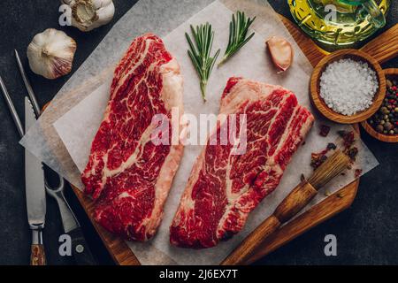 Bistecca di manzo marmorizzato con utensili e spezie per la cottura Foto Stock