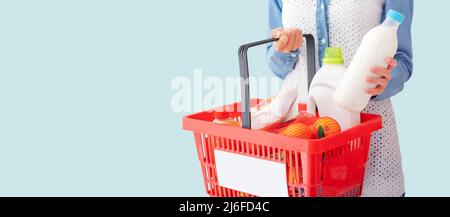 La donna gli acquisti al supermercato, ella è portante un carrello e a prendere una bottiglia di latte Foto Stock