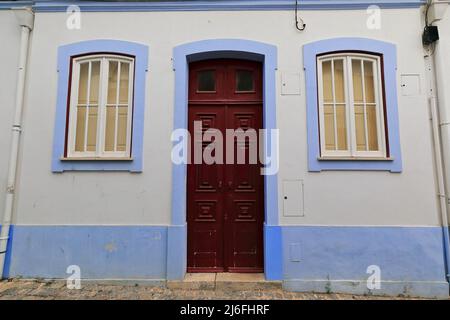 Mauve incorniciata parete bianca-una storia Townhouse-porta in legno maroon. Lagos-Portogallo-223 Foto Stock