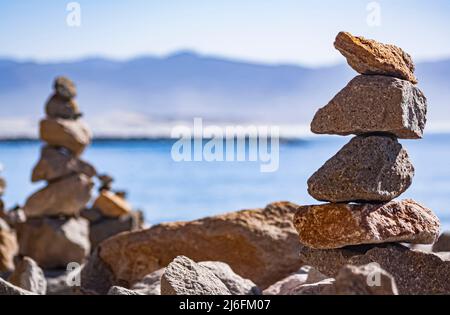 Rocce impilate bilanciate sulla spiaggia Foto Stock