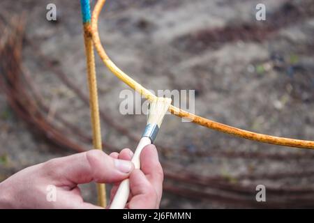 un uomo dipinge un telaio di ferro con vernice gialla e blu. fuoco selettivo Foto Stock