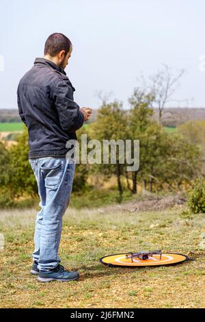 Uomo accanto a un drone e guidare il telecomando per decollo. Foto Stock