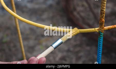 un uomo dipinge un telaio di ferro con vernice gialla e blu. fuoco selettivo Foto Stock