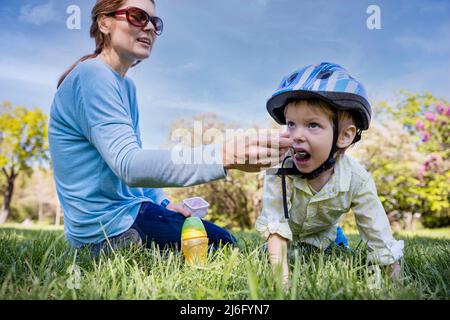 La madre nutre il suo piccolo figlio irrequieto all'aperto nel parco Foto Stock