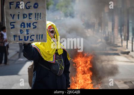 Un manifestante giallo con una bandiera francese cammina accanto a mobili di strada brucianti che è stato messo a fuoco per impedire alla polizia di andare avanti. Migliaia di persone si sono svolte per i raduni del giorno di maggio. I manifestanti hanno marciato attraverso la città chiedendo il progresso sociale in una società ansiosa per il futuro del pianeta e di un mondo in pace. Storicamente il 1st maggio segna la Giornata Internazionale del lavoro che commemora i lavoratori e la classe operaia. Foto Stock