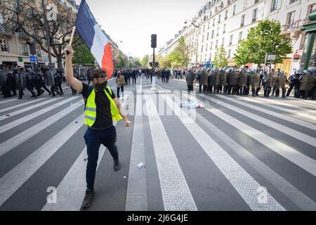 Un manifestante giallo con una bandiera francese cammina oltre la prima linea della polizia durante la dimostrazione. Migliaia di persone si sono svolte per i raduni del giorno di maggio. I manifestanti hanno marciato attraverso la città chiedendo il progresso sociale in una società ansiosa per il futuro del pianeta e di un mondo in pace. Storicamente il 1st maggio segna la Giornata Internazionale del lavoro che commemora i lavoratori e la classe operaia. Foto Stock