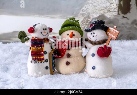 Trio di amici di neve felice abbracciano come si levano in piedi nel mezzo di un paesaggio invernale nevoso Foto Stock