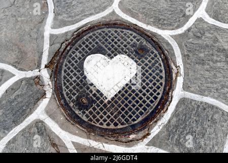 Il cuore bianco è dipinto su una copertura di tombino Foto Stock