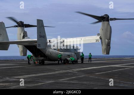 PHILIPPINE SEA (6 aprile 2022) i marinai si incatenano e concatenano un CMV-22B Osprey, assegnato ai 'Titans' della Fleet Logistics Multi-Mission Squadron (VRM) 30, sul ponte di volo del vettore aereo di classe Nimitz USS Abraham Lincoln (CVN 72). Abraham Lincoln Strike Group è in fase di implementazione pianificata nell'area delle operazioni della flotta USA 7th per migliorare l'interoperabilità attraverso alleanze e partnership, fungendo da forza di risposta pronta a supportare una regione indopacifica libera e aperta. (STATI UNITI Foto Navy di Mass Communication Specialist 3rd Classe Javier Reyes) Foto Stock