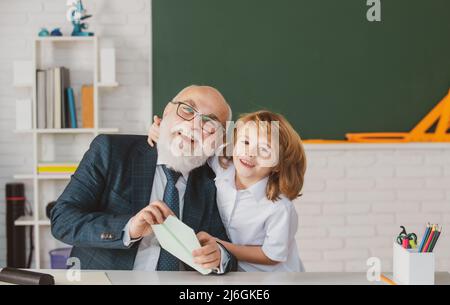 Vecchio insegnante e giovane scolaro. I bambini imparano la scienza. Giornata degli insegnanti. Foto Stock