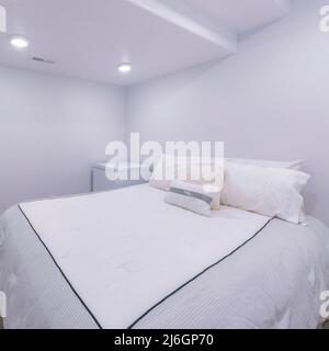 Camera da letto quadrata bianca interna con pavimento in legno e porta bianca Foto Stock