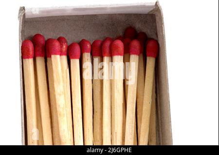 primo piano di partite impilate con teste di match rosse in scatola di fiammiferi aperta su sfondo bianco Foto Stock