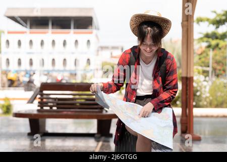 Giovane donna viaggiatore con zaino in cerca di mappa in attesa di treno, saccopelatore asiatico sulla piattaforma ferroviaria alla stazione ferroviaria. Vacanza, viaggio Foto Stock