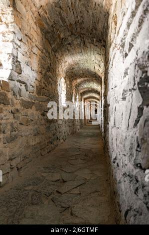 Tunnel in pietra. Stretto corridoio con balcone con pareti in mattoni nel castello Foto Stock