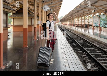 Donna asiatica zaino in spalla viaggiatore piano vacanza estate dopo coronavirus. Turisti vuoti sulle piattaforme ferroviarie. Utilizzare il treno autobus sostenibile Foto Stock