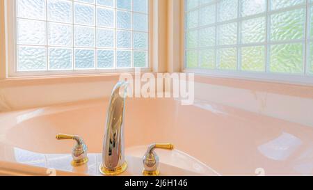 Panorama angolo vasca da bagno con ponte montato diffuso in acciaio inox con rubinetto d'oro Foto Stock