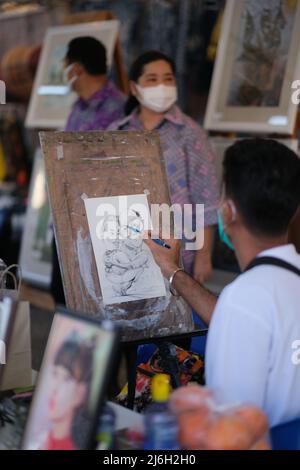 Pattaya, Chonburi Thailandia - Novembre 26 2021: Artista di strada sta disegnando un fumetto divertente per una coppia di clienti Foto Stock