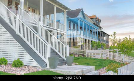 Panorama Whispy nuvole bianche tre grandi case con recinzione di picket bianco e verande all'ingresso di Daybreak, Utah Foto Stock