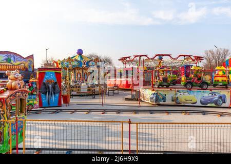 Le giostre e le giostre per bambini sono chiuse e vuote. Gioia e divertimento per i bambini. Giostre luminose e carrozze per il trasporto di bambini sono Foto Stock