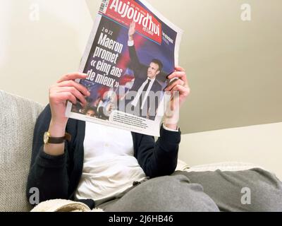 Parigi, Francia - 25 apr 2022: Donna che legge su un comodo divano ultimo giornale Aujord'hui, coprire con la Francia presidente in carica Emmanuel Macron dopo aver battuto Marine le Pen per un secondo quinquennio Foto Stock