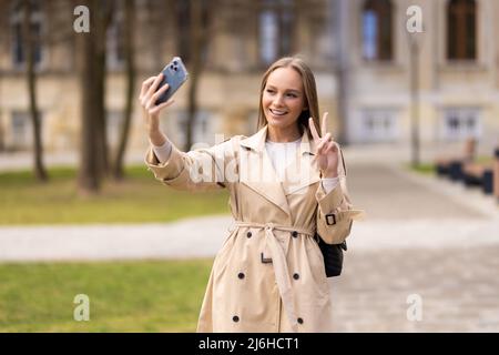 Ragazza giovane prendere selfie da mani con il telefono acceso estate città street. La vita urbana concetto. Foto Stock