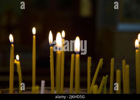 Acceso candele di cera in una chiesa di bruciare nel crepuscolo Foto Stock