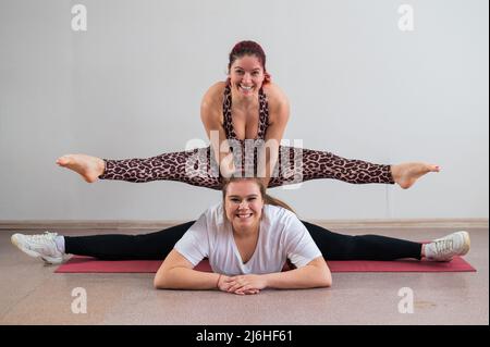 Donna caucasica che fa un cavalletto sulla sua amica. Acrobazie di coppia. Foto Stock