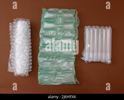Un sacchetto di pimply e cuscini d'aria per imballare i pacchi fragili su uno sfondo marrone. Vari tipi di sacchetti da imballaggio in polipropilene. Bolla e perfo Foto Stock