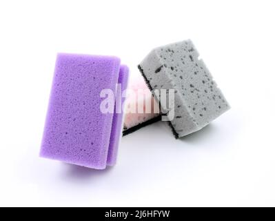 Spugne colorate per lavastoviglie su sfondo bianco. Spugne per il lavaggio di piatti e altre esigenze domestiche. Spugna grigia e viola leggermente inclinata Foto Stock