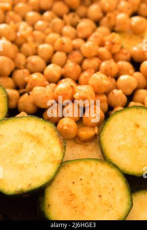 Ceci speziati e zucchine affettate su una teglia da forno pronta per essere messa in forno Foto Stock