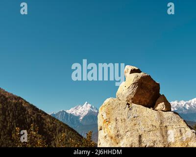 enormi pietre di preghiera sotto il cielo blu con la catena montuosa di meili innevate sullo sfondo, sichuan, cina Foto Stock