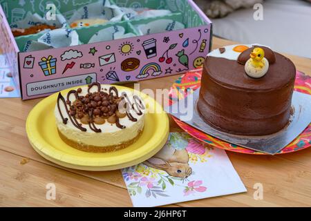 Torta al cioccolato di Pasqua, cheesecake e ciambelle presentate su un tavolo esterno Foto Stock