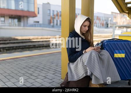 Depressa immigrata Ucraina giovane donna seduta e in attesa alla stazione ferroviaria. Foto Stock