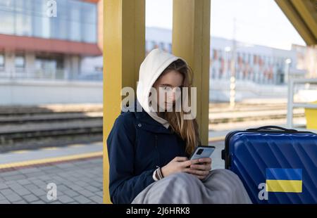 Depressa immigrata Ucraina giovane donna seduta e in attesa alla stazione ferroviaria. Foto Stock