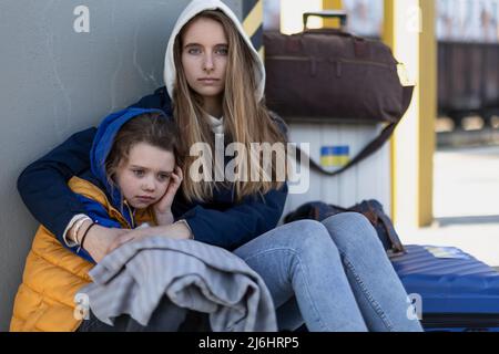 Depressi immigrati ucraini seduti e in attesa alla stazione ferroviaria. Foto Stock