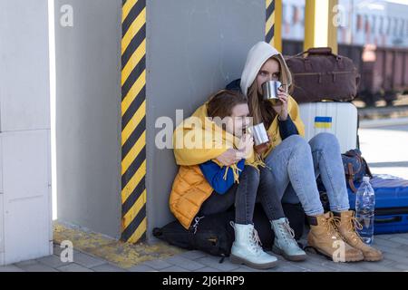 Depressi immigrati ucraini seduti e in attesa alla stazione ferroviaria. Foto Stock