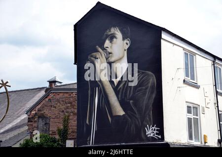 Un murale a Macclesfield dell'artista di strada Akse in omaggio a Ian Curtis, cantante principale della divisione di gioia, che è stato sopportato nella città di Cheshire. Foto Stock