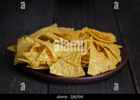 Il più famoso snack messicano, nachos fatta con il mais tortilla chips o totopos su sfondo di legno. Foto Stock