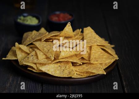 Il più famoso snack messicano, nachos fatta con il mais tortilla chips o totopos su sfondo di legno. Foto Stock