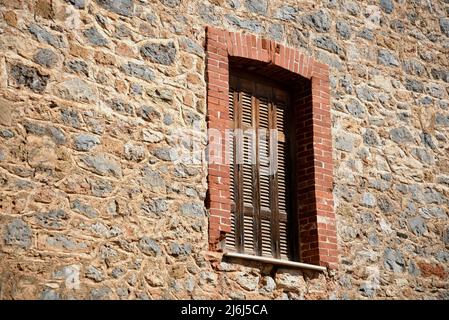 Vecchia casa rurale tradizionale finestra in legno con persiane su un muro di pietra artigianale a Monemvasia, Laconia Peloponneso, Grecia. Foto Stock