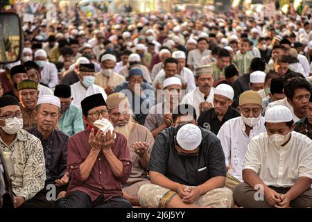 Gli uomini musulmani offrono preghiere durante Eid 1443 Hijriyah / 2022 d.C. vicino ad una chiesa in Jatinegara. Quest'anno, il governo indonesiano ha permesso che le preghiere di Eid si tenevano insieme dopo due anni di cancellazione a causa della pandemia del Covid-19. Foto Stock